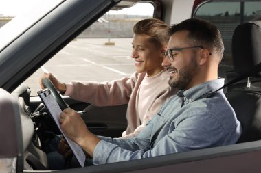 Ehliyet kursu. Otoparkta sınavı geçen mutlu öğrenci.