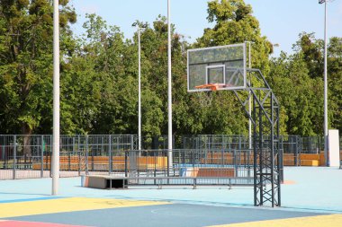Güneşli bir günde arka tahtası açık olan boş basketbol sahası.