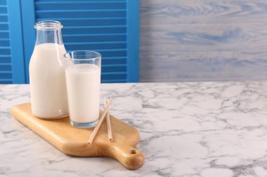 Lezzetli sütlü cam eşyalar ve beyaz mermer masa üzerinde pipetler, metin için yer