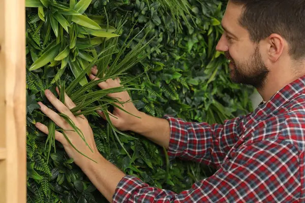 stock image Man installing green artificial plant wall panel, closeup