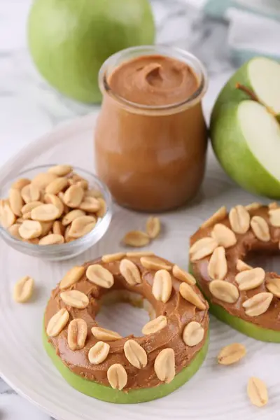 Fresh green apples with peanut butter and nuts on table, closeup