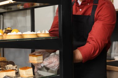 İşçi kafede vitrinden reçelli leziz bir cheesecake alıyor.