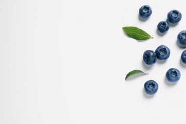 Beyaz arka planda yeşil yapraklı taze yaban mersinleri. Metin için boşluk