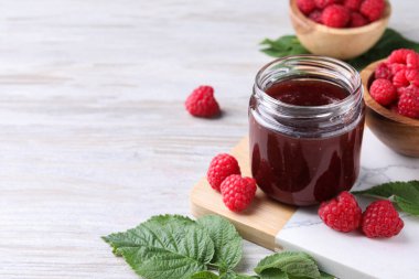 Lezzetli ahududu reçeli, taze böğürtlen ve açık ahşap masada yeşil yapraklar. Metin için boşluk