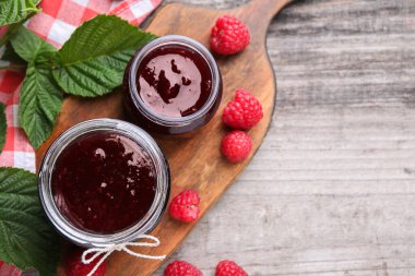 Lezzetli ahududu reçeli, taze böğürtlen ve ahşap masada yeşil yapraklar, düz yatak. Metin için boşluk