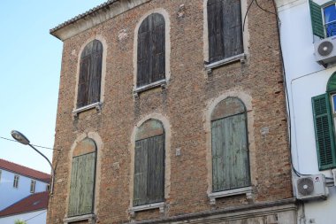 Pencerelerinde kapalı ahşap panjurlar olan eski tuğla binanın dışı.