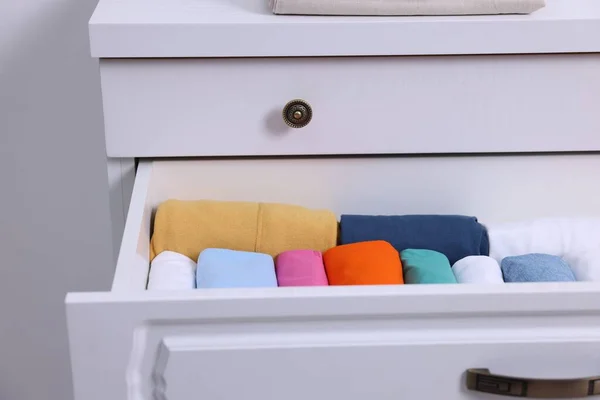 Open drawer with rolled shirts indoors. Organizing clothes