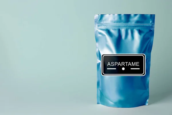 Aspartame. Blue foil package with artificial sweetener on light background, space for text