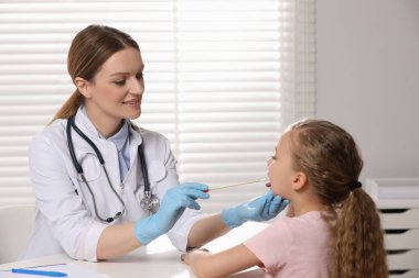 Doktor içeride kızın ağız boşluğundan örnek alıyor.