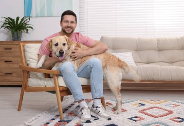 Adam evde sevimli Labrador Retriever köpeğine sarılıyor. Sevimli hayvan