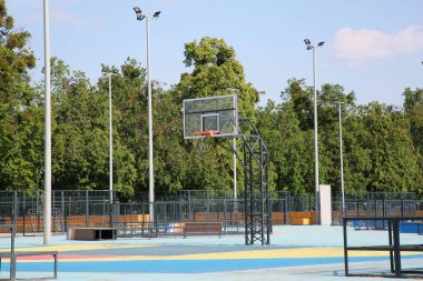 Güneşli bir günde arka tahtası açık olan boş basketbol sahası.