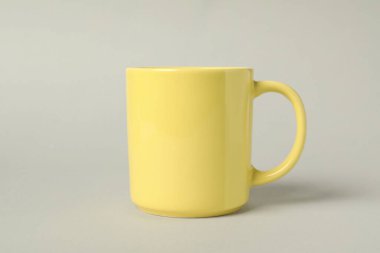 Açık gri arkaplanda bir sarı seramik bardak