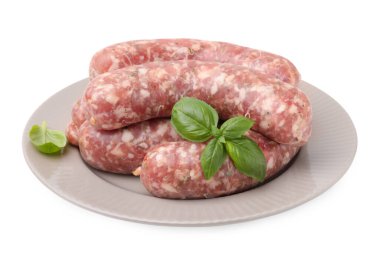 Beyaz üzerine izole edilmiş çiğ sosis ve fesleğen yaprakları.