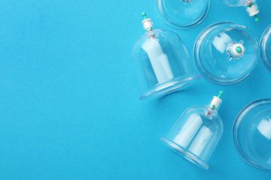 Açık mavi arkaplanlı plastik bardaklar, metin için yeri olan düz yataklar. Fincan terapisi.