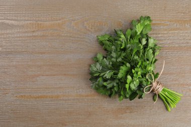 Açık ahşap masa üzerinde yeşil maydanoz yaprakları, üst manzara. Metin için boşluk