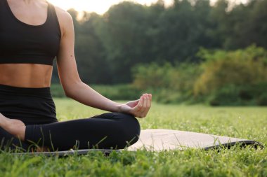 Dışarıdaki yoga minderinde Padmasana antrenmanı yapan bir kadın, yakın çekim ve mesaj için yer. Lotus pozu