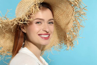 Açık mavi arka planda hasır şapkalı güzel bir kadın.