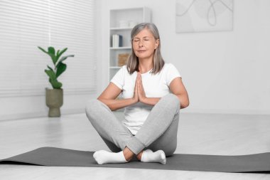 Son sınıf öğrencisi kadın evde yoga yapıyor.