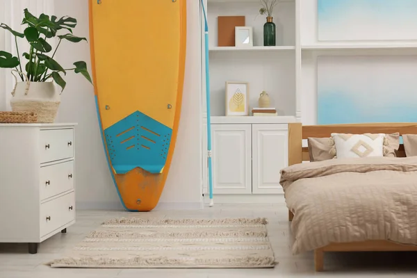 SUP board, bed and furniture in room. Interior design