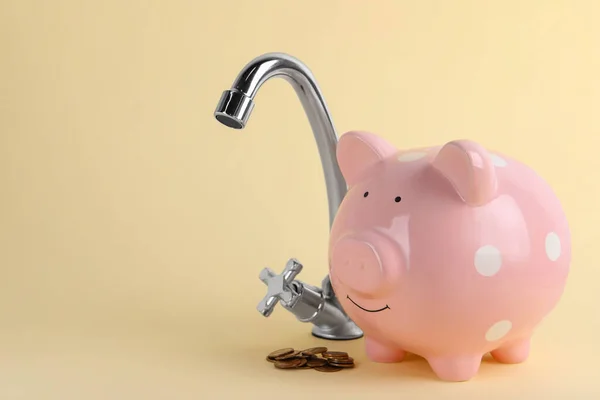 Water scarcity concept. Piggy bank, tap and coins on beige background, space for text