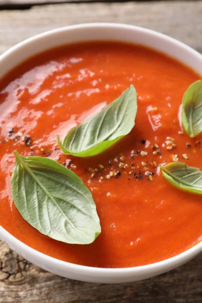 Delicious tomato soup with basil and spices on table, closeup