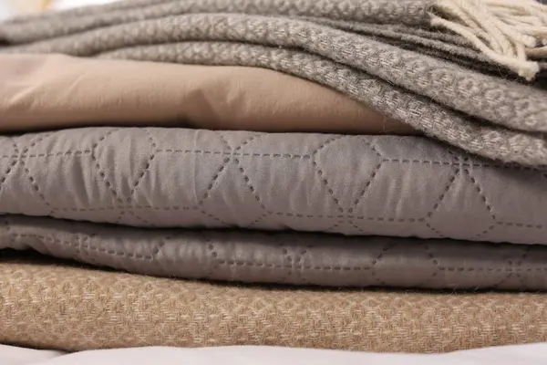 Stack of different folded blankets, closeup. Home textile