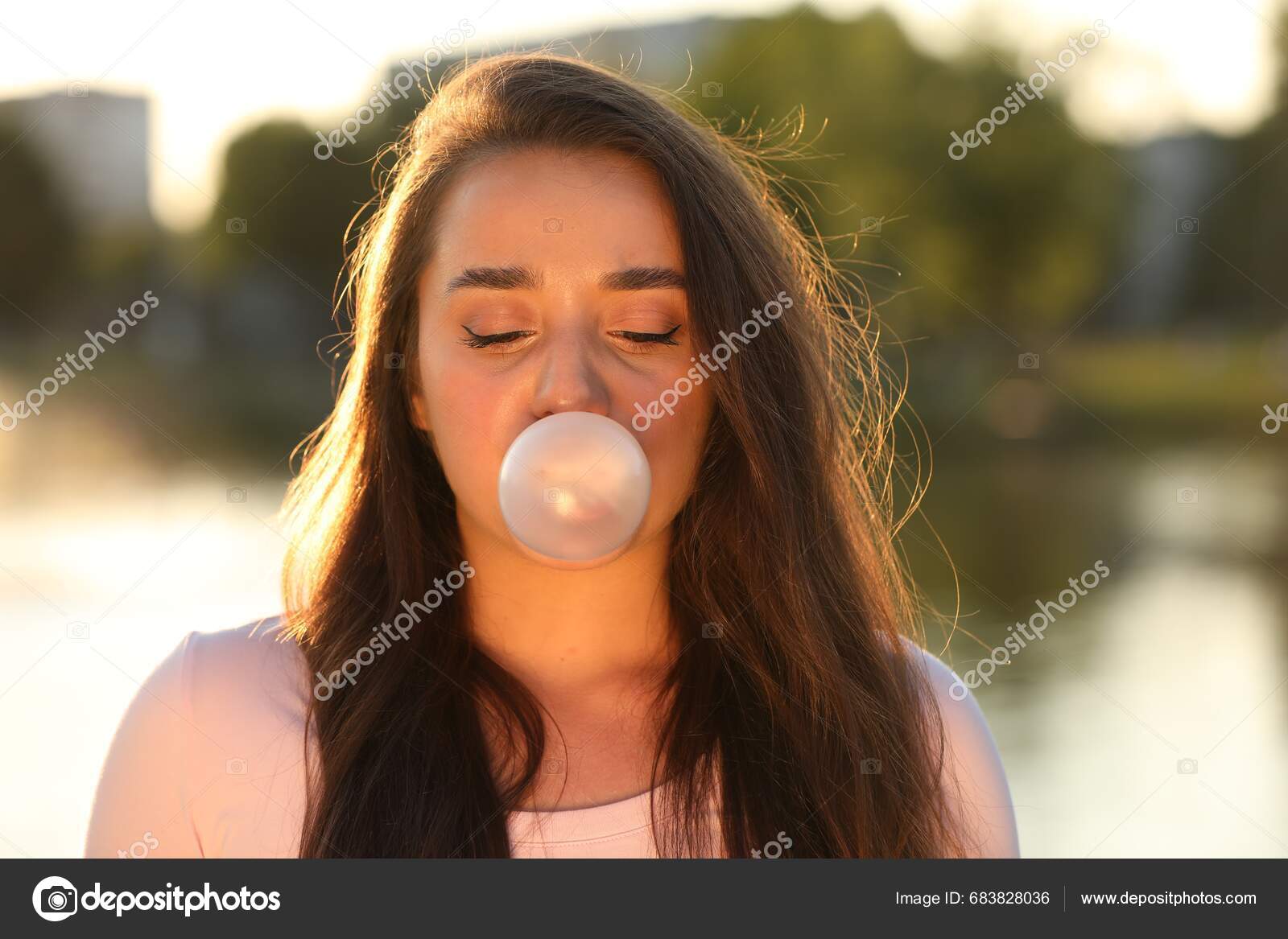 Beautiful Young Woman Blowing Bubble Gum Outdoors Stock Photo by