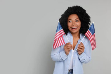 4 Temmuz - ABD 'nin Bağımsızlık Günü. Açık gri arkaplanda Amerikan bayrakları olan mutlu kadın, mesaj için boşluk