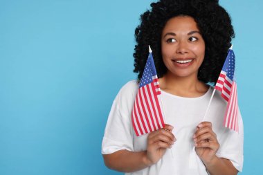 4 Temmuz - ABD 'nin Bağımsızlık Günü. Açık mavi arka planda Amerikan bayrakları olan mutlu kadın, metin için boşluk