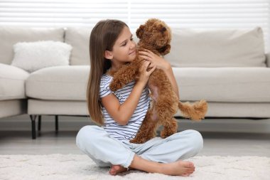 Evde halı üzerinde şirin köpek yavrusu olan küçük bir çocuk. Sevimli hayvan