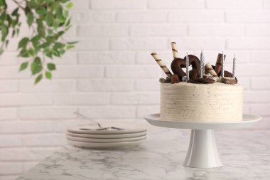 Tatlı ile süslenmiş lezzetli pasta ve beyaz mermer masa üzerinde mumlar, metin için yer