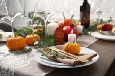 Güzel bir sonbahar sofrası. Tabaklar, çatal bıçak, gözlük, balkabağı ve çiçek dekoru.