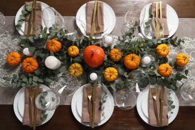 Güzel bir sonbahar sofrası. Tabaklar, çatal bıçak takımı, bardaklar, balkabakları ve çiçek dekoru.