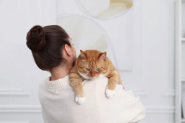Woman with cute cat at home, back view