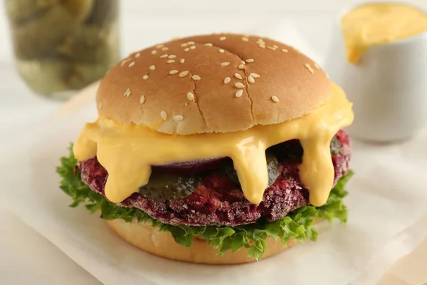 Tasty vegetarian burger with beet patty on white table, closeup