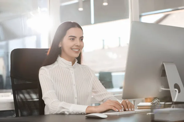 Happy woman using modern computer at black desk in office