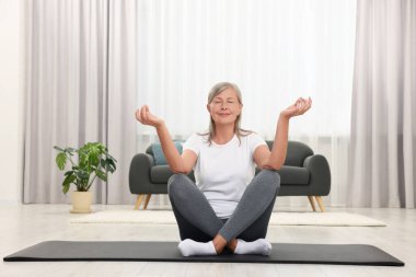 Mutlu son sınıf öğrencisi kadın evde yoga yapıyor.
