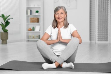 Mutlu son sınıf öğrencisi kadın evde yoga yapıyor.