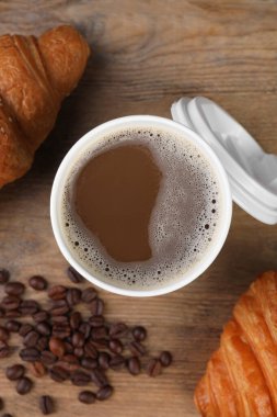 Paket kahve. Lezzetli içecekli kağıt bardak, kruvasan ve fasulye ahşap masada, düz yatıyordu.