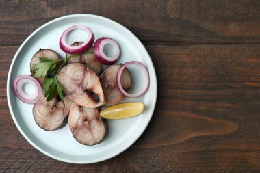 Soğan halkalı lezzetli tuzlu uskumru dilimleri, ahşap masada maydanoz ve limon dilimleri, üst manzara. Metin için boşluk