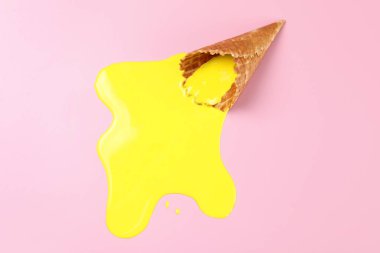 Pembe arka planda erimiş dondurma ve gofret külahı.