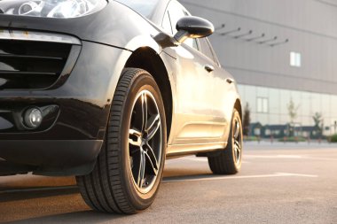 Asfalt yolda park edilmiş modern siyah araba.