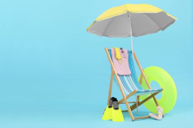 Güverte koltuğu, şemsiye ve plaj aksesuarları açık mavi arka plana karşı, mesaj için yer. Yaz tatili