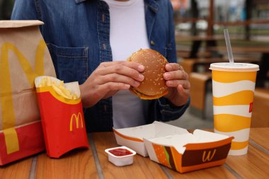 Lviv, Ukrayna - 9 Ekim 2023: Tahta masada McDonald 's menüsü olan kadın, yakın plan