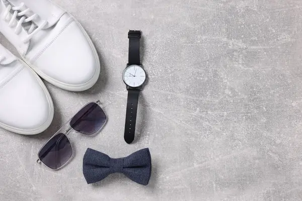 Stylish blue bow tie, shoes, sunglasses and wristwatch on light grey table, flat lay. Space for text