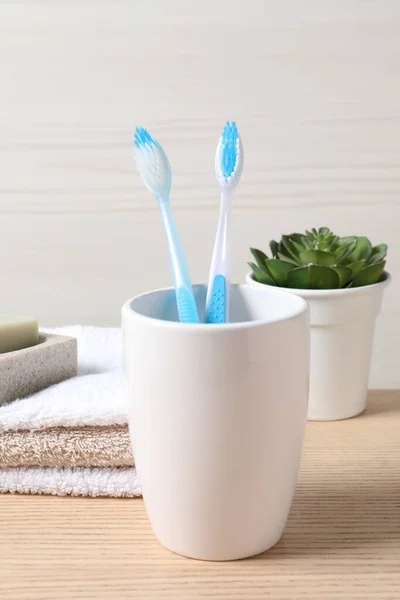 Plastic toothbrushes in holder on wooden table
