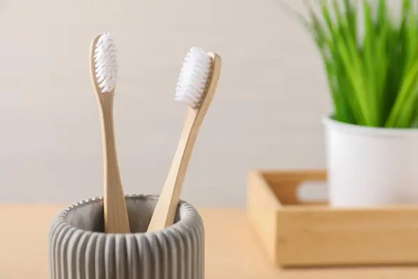 Bamboo toothbrushes in holder against light background, closeup