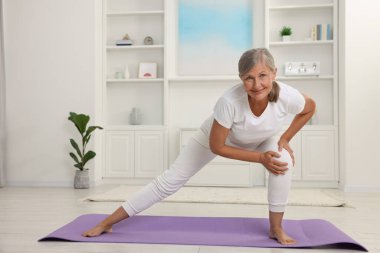 Mutlu son sınıf öğrencisi kadın evde yoga yapıyor.