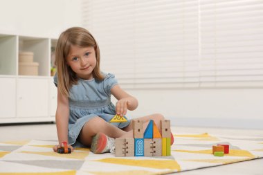 Şirin küçük kız içeride tahta oyuncaklarla oynuyor, mesaj için yer var.