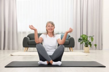 Mutlu son sınıf öğrencisi kadın evde yoga yapıyor.